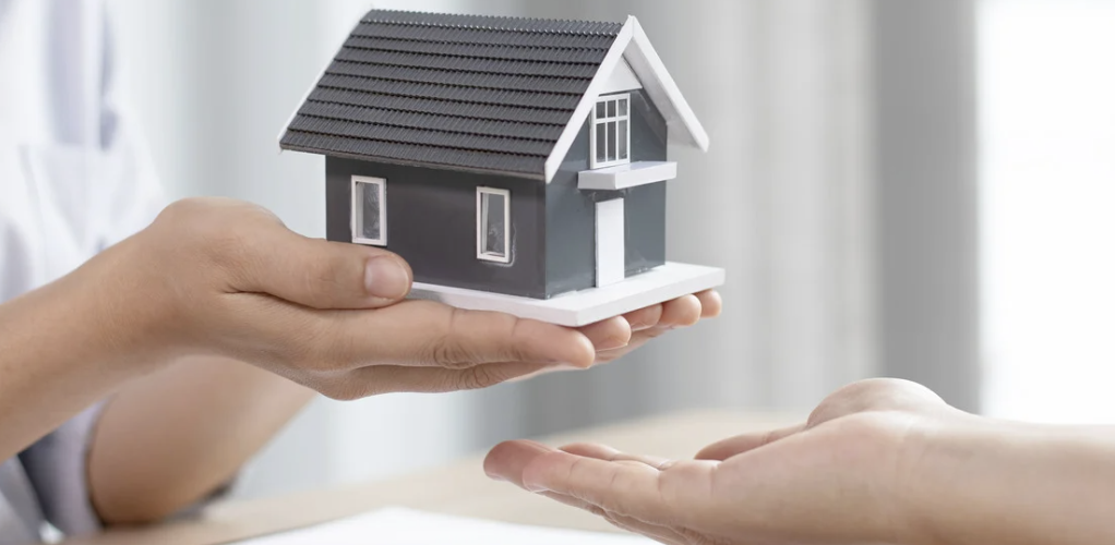 An agent holding a small replica of a home in her palm